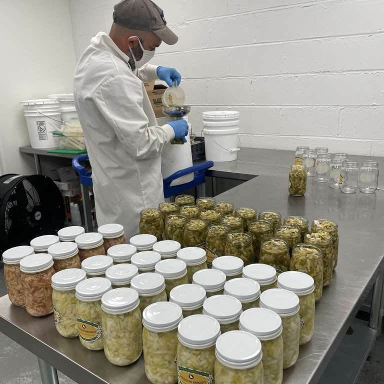 A man bottling sauerkraut in the CoMo Cooks Kitchen.